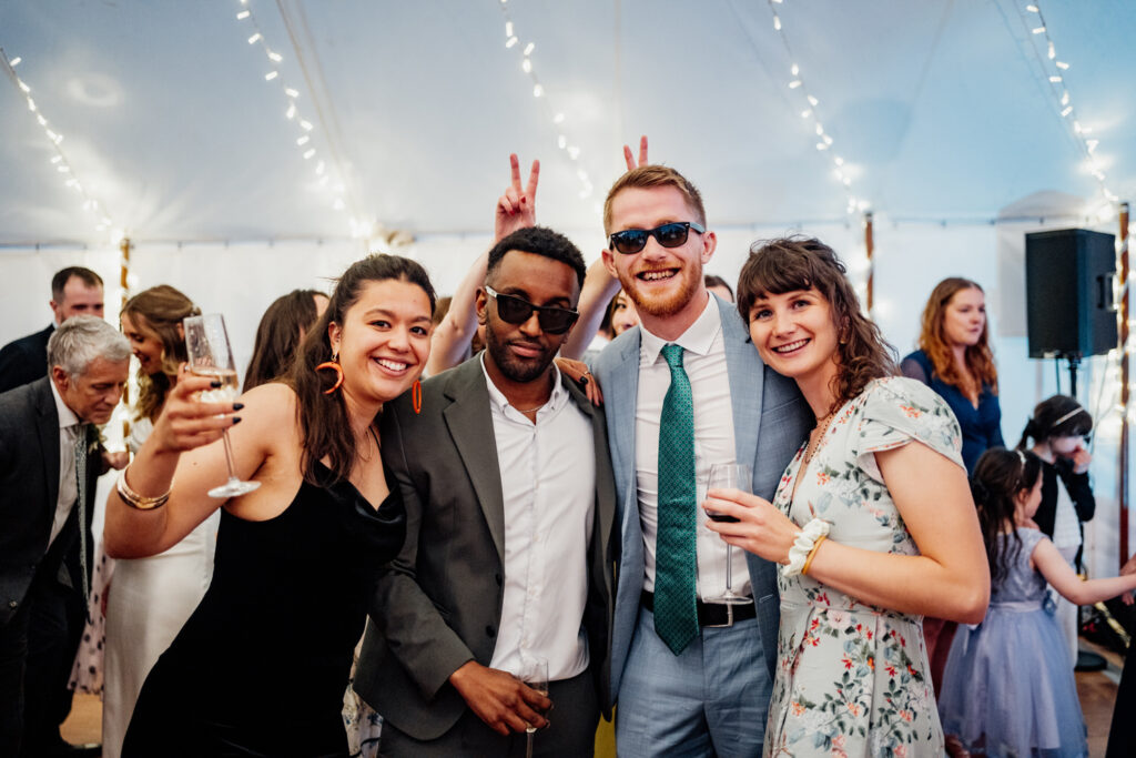 guests posing for group photos in wedding marquee