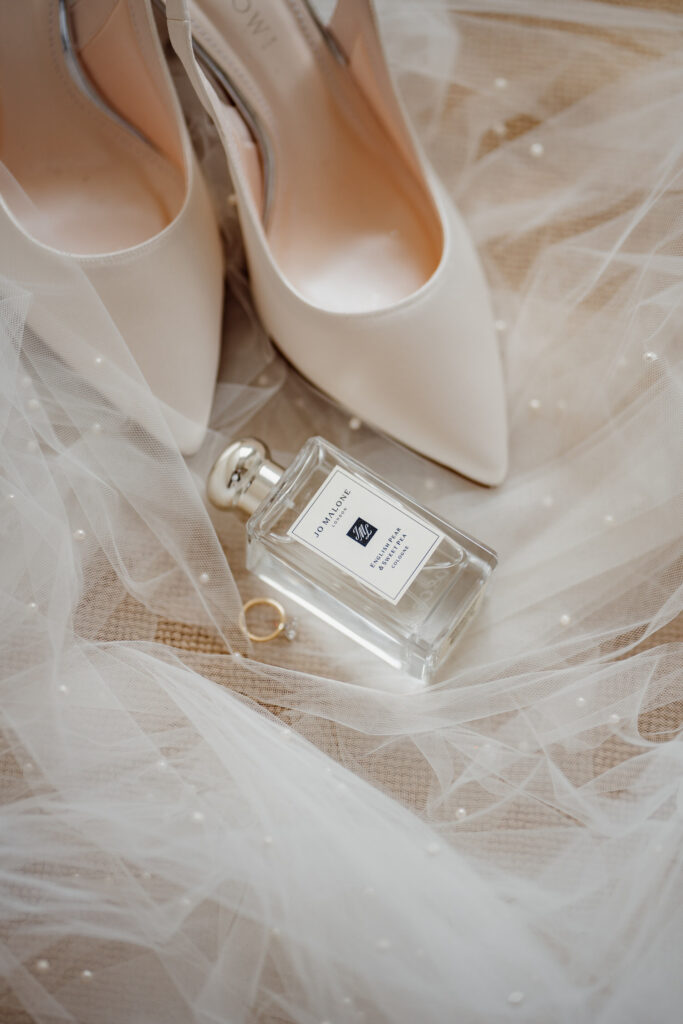 flatlay of white wedding shoes, jo malone perfume and wedding shoes