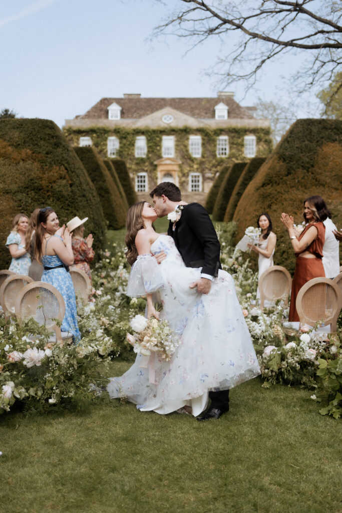 Bride and groom perform a dip kiss in front of Cornwell Manor during their ceremony