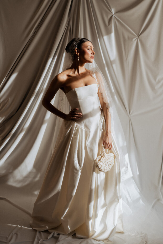 Editorial photo of bride in her wedding dressing holding a fashionable handbag