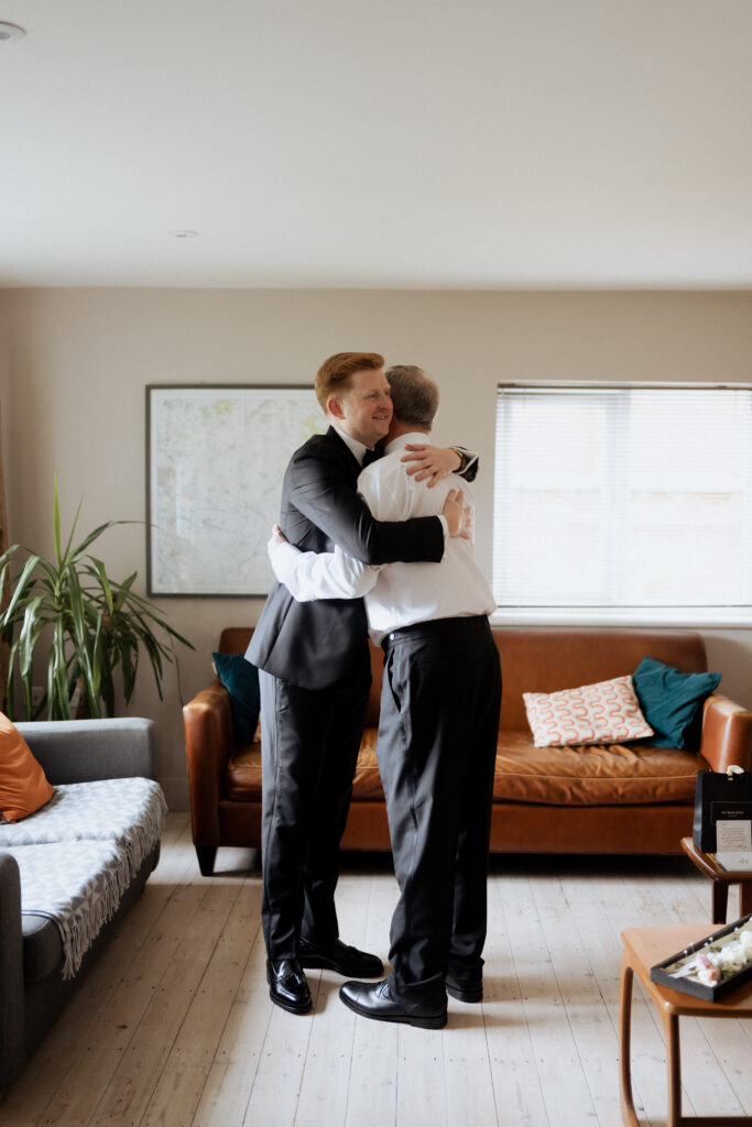 Groom and father hugging, taken by a second photographer